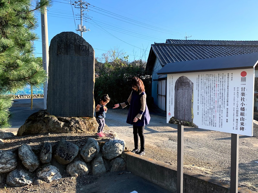 甘楽社小幡組由来碑の前でお母さんが娘に手を差し伸べる